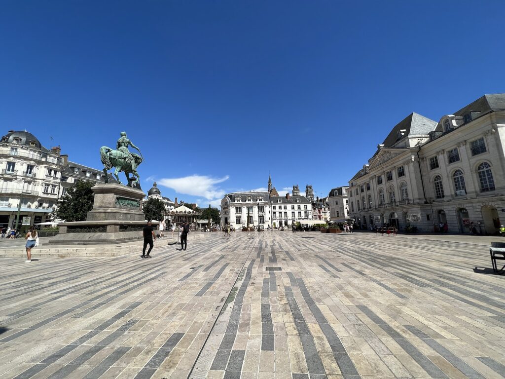 Place pavée d’Orléans avec statue équestre au centre et bâtiments historiques, ambiance touristique et claire. activité orléans adulte intégrée naturellement dans la description.